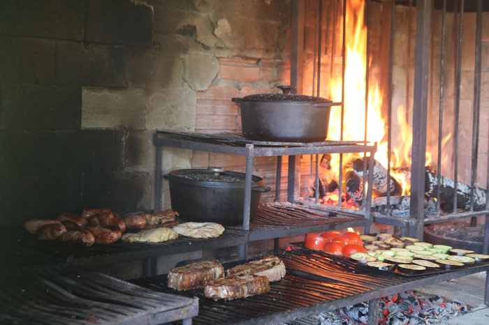 Parrilla de lenha com cortes nobres na grelha e chama ao fundo — Recanto das Seriemas, São Pedro SP
