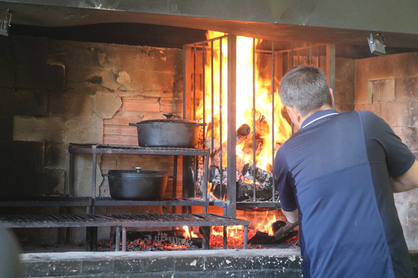 Parrilla de lenha em operação — panelas de ferro e chama alta no Recanto das Seriemas