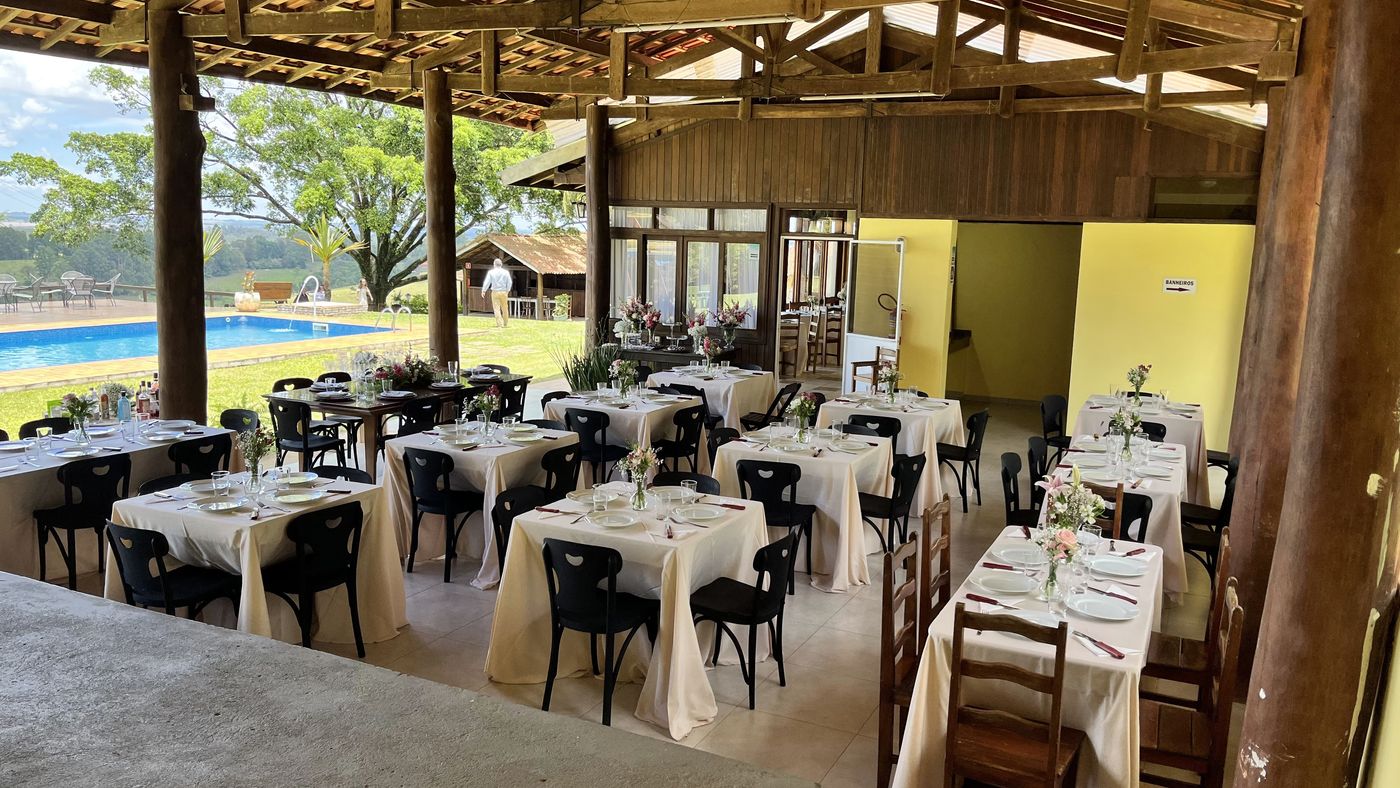 Salão coberto montado para recepção de casamento com mesas postas e vista para o vale — Recanto das Seriemas