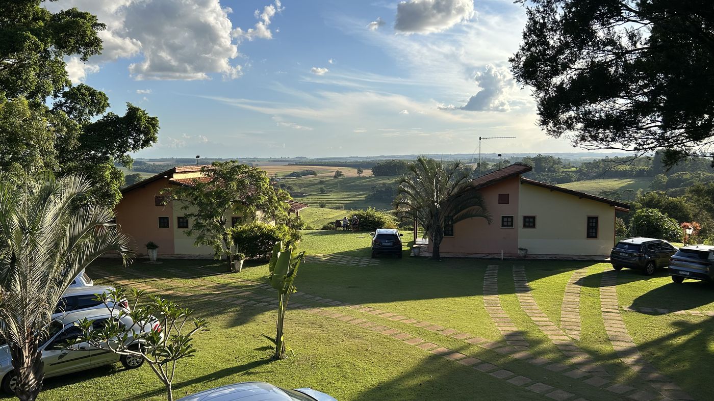 Suítes do Recanto das Seriemas ao pôr do sol com seriemas no gramado e o vale da Serra do Itaqueri ao fundo