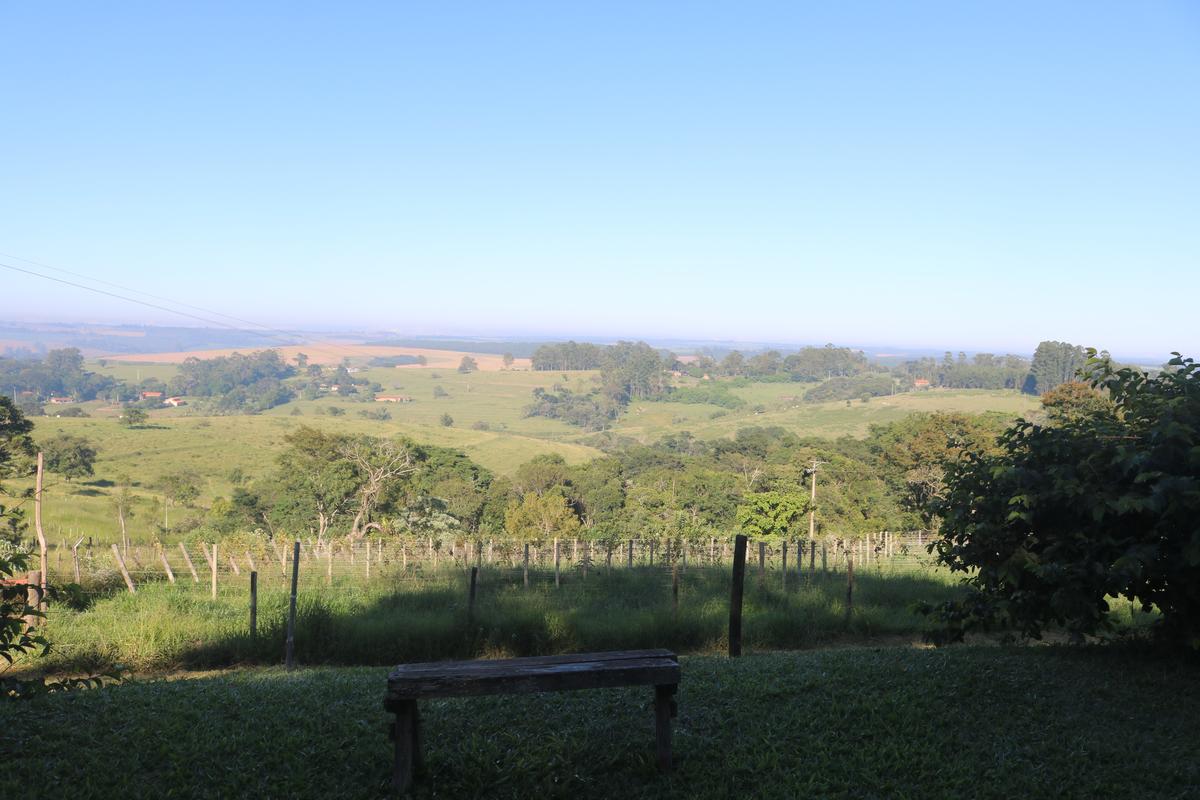 Varanda da suíte ao pôr do sol com vista panorâmica para o vale da Serra do Itaqueri — Recanto das Seriemas