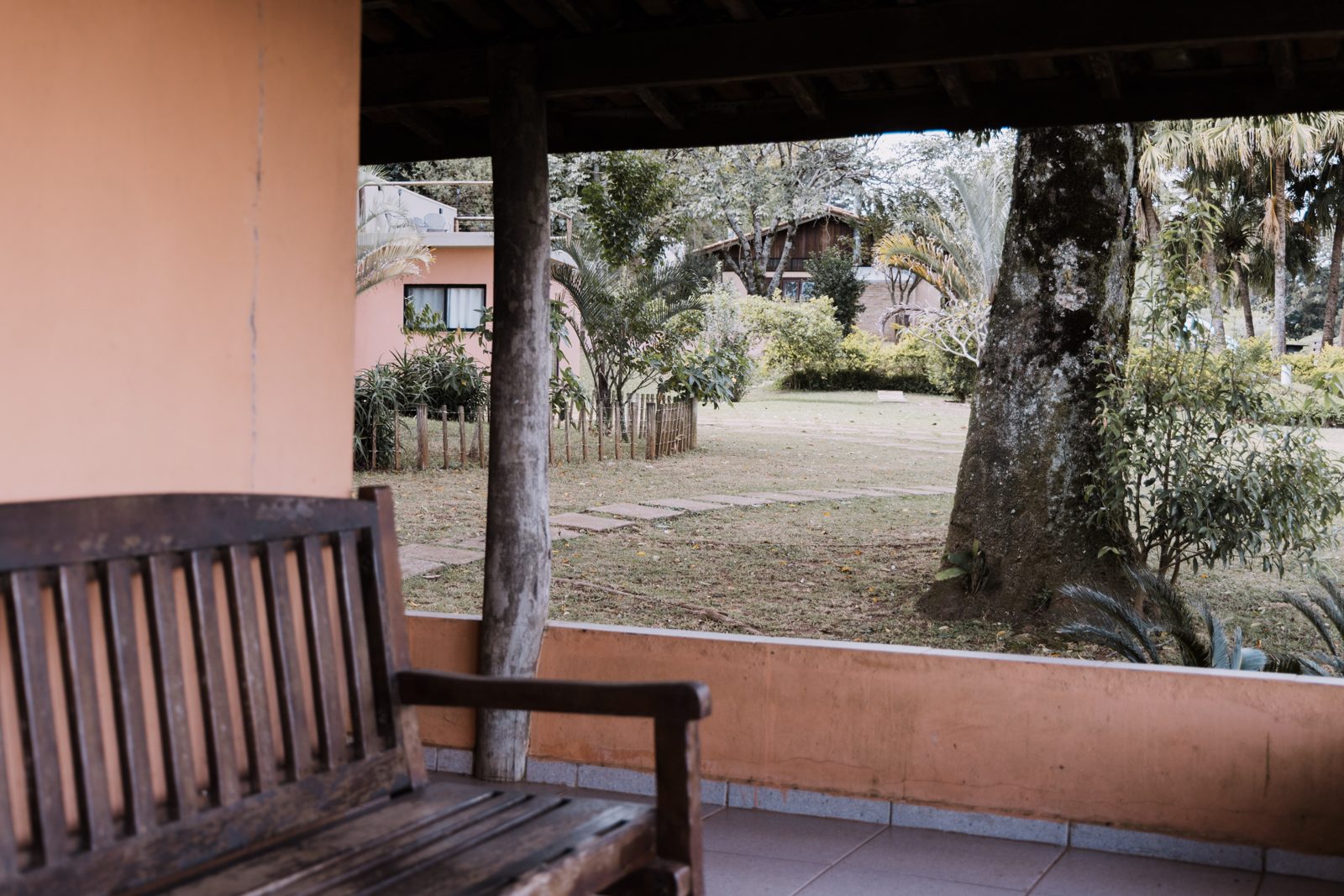 Varanda da suíte com banco de madeira e vista para o jardim e o vale da Serra — Recanto das Seriemas